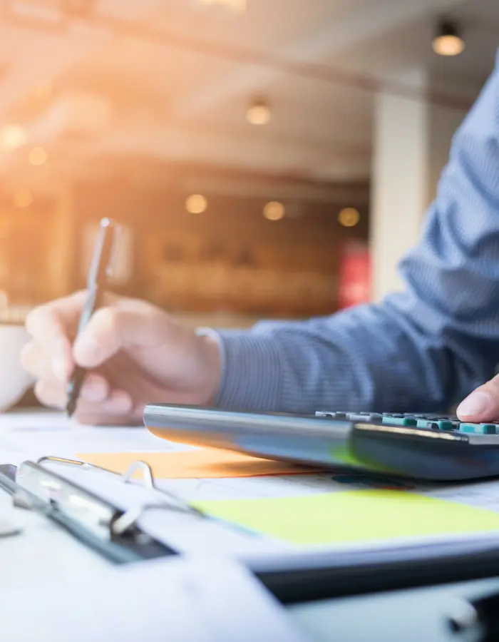 Bureau de travail avec calculatrice, mais qui tient un crayon et dossiers de finances